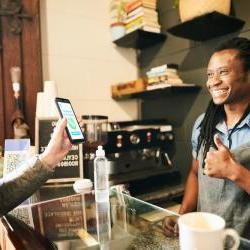 black barista gives thumbs up to customer who paid on her phone