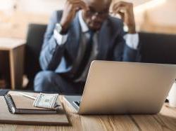 Black man working on computer with tired expression